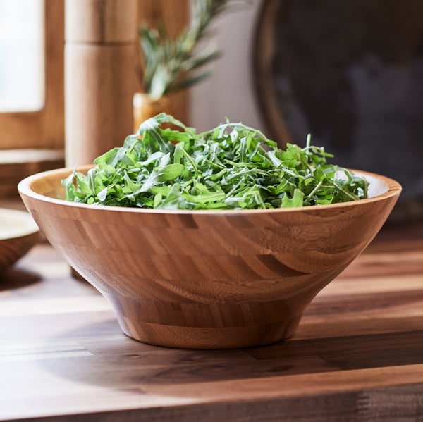 Saladier en bois rempli de salade sur un plan de travail en bois