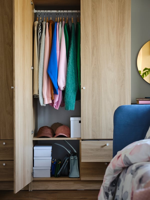 Clothes and three white SPINNROCK boxes with compartments in an oak effect VILHATTEN wardrobe with two doors and two drawers.