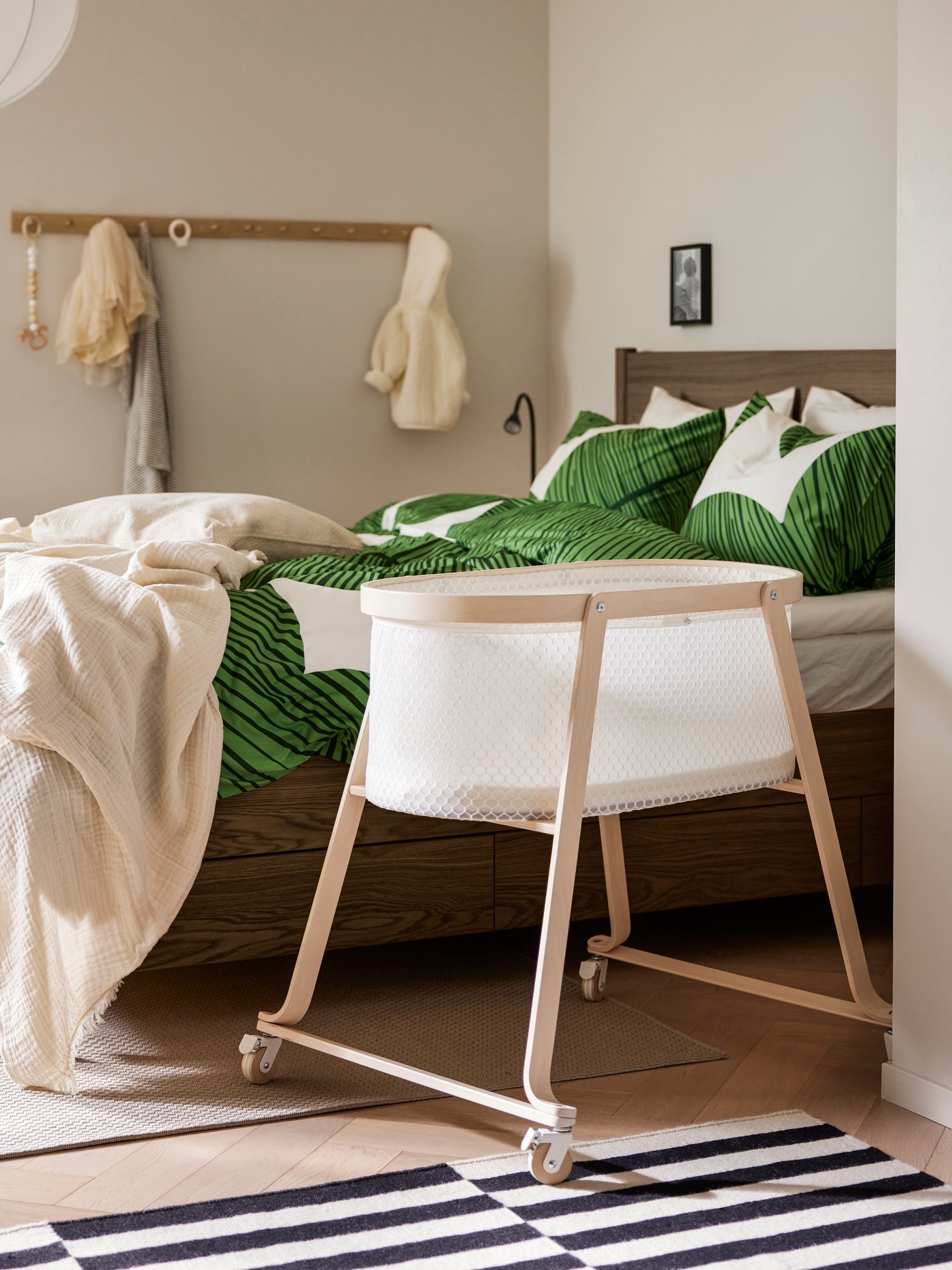 En ÄLSKVÄRD spjälsäng står i ett skandinaviskt sovrum med gröa och vita sängkläder.