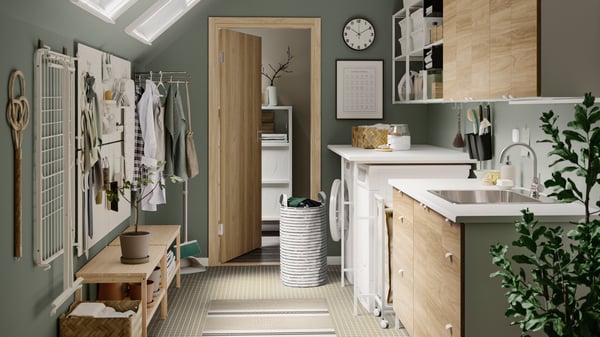 Une salle de lavage verte avec des meubles en bois clair. Différentes plantes sont disposées dans la pièce.