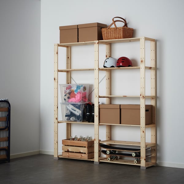 Scaffale HEJNE con alcuni contenitori e scatole in plastica, cartone e legno, degli skateboard, dei caschi e un cestino.