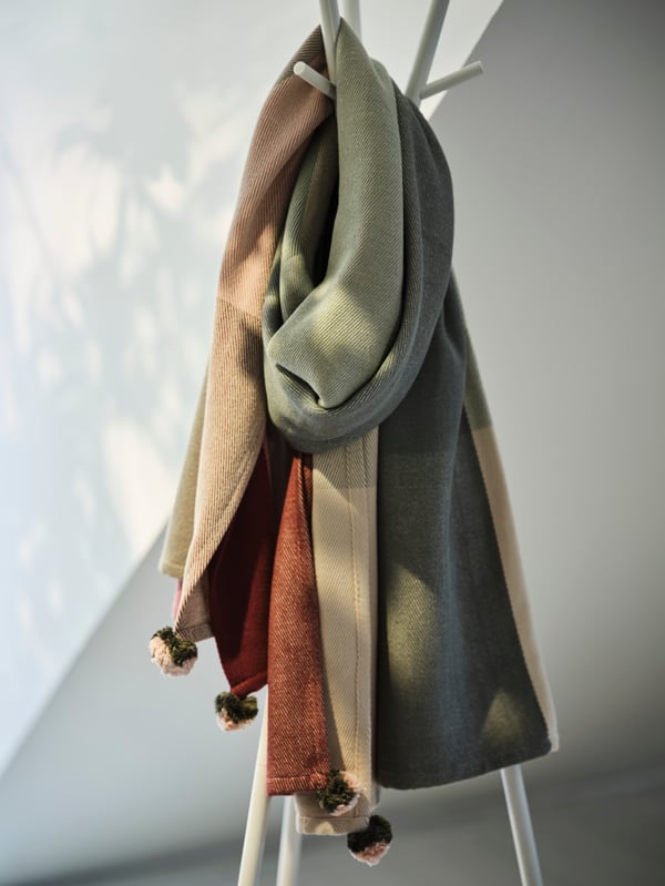 Perchero blanco de pie con múltiples ganchos superiores e intermedios para colgar abrigos, chaquetas y accesorios.