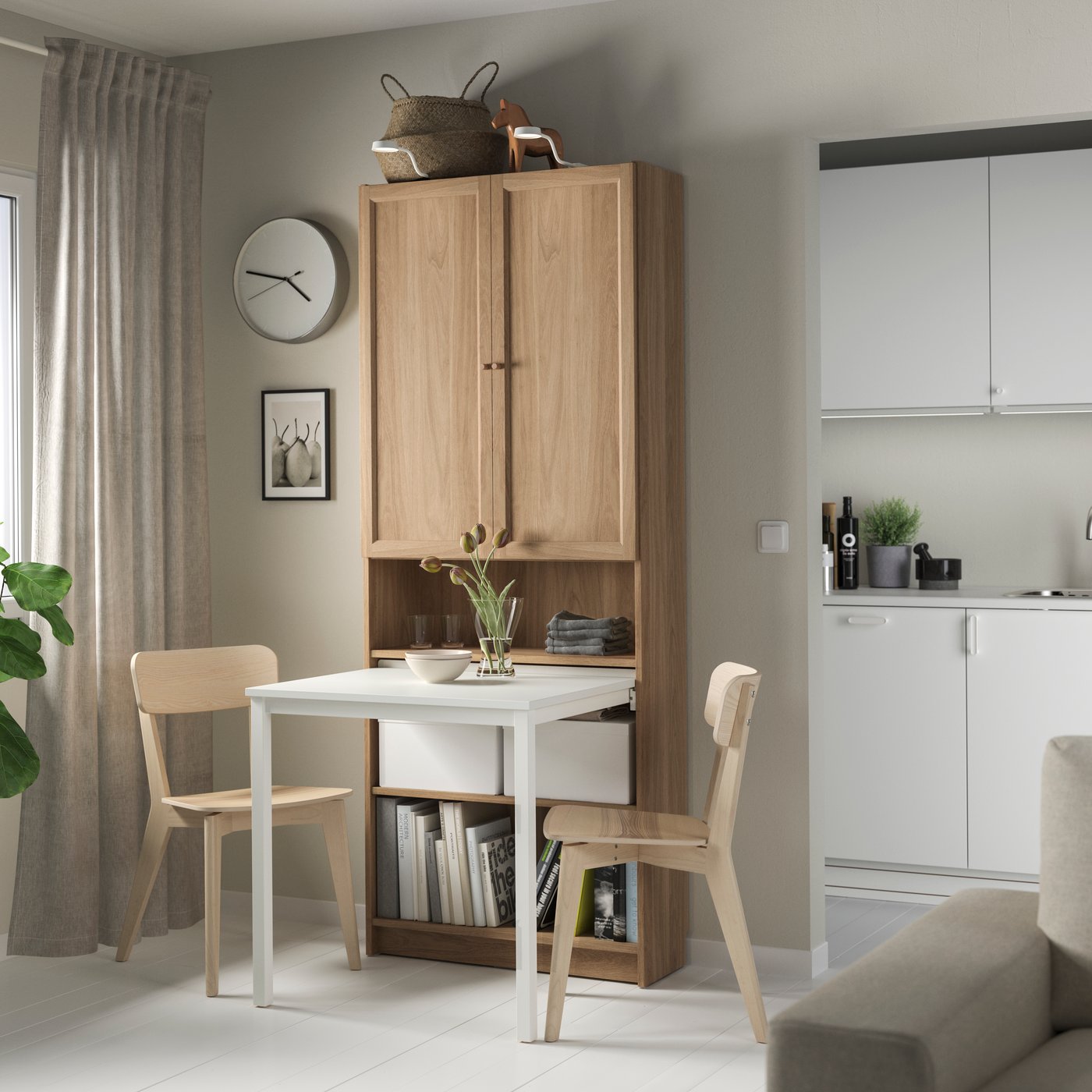 Ein teilweise geschlossenes eichefarbenes BILLY Bücherregal, mit Schublade und einem Tisch, in einem Esszimmer. Daneben stehen Esszimmerstühle.