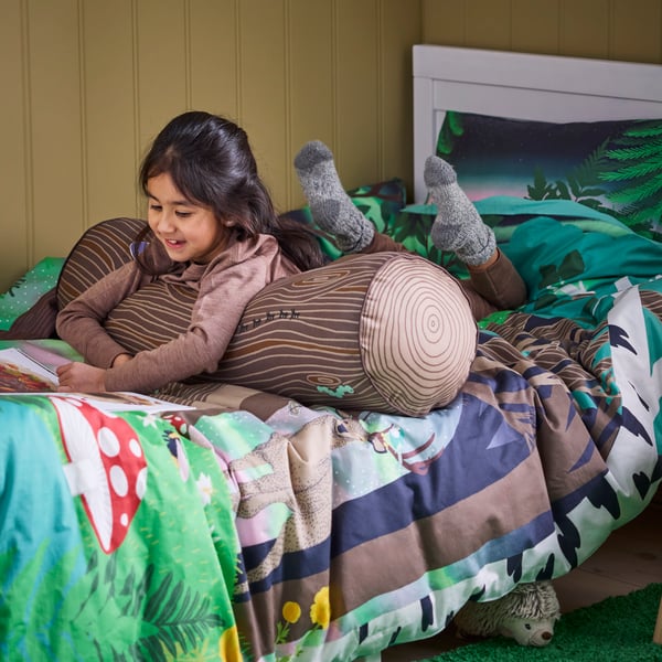 A cylinder shaped/brown SKOGSDUVA cushion in the childrens room