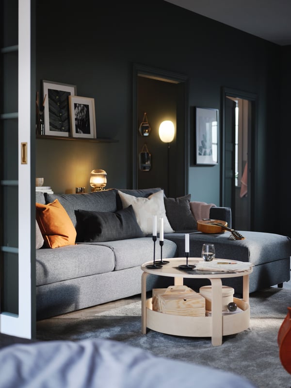 Ein hellgraues Schlafsofa in L-Form aus unserer VIMLE Serie mit verschiedenen bunten Zierkissen.
