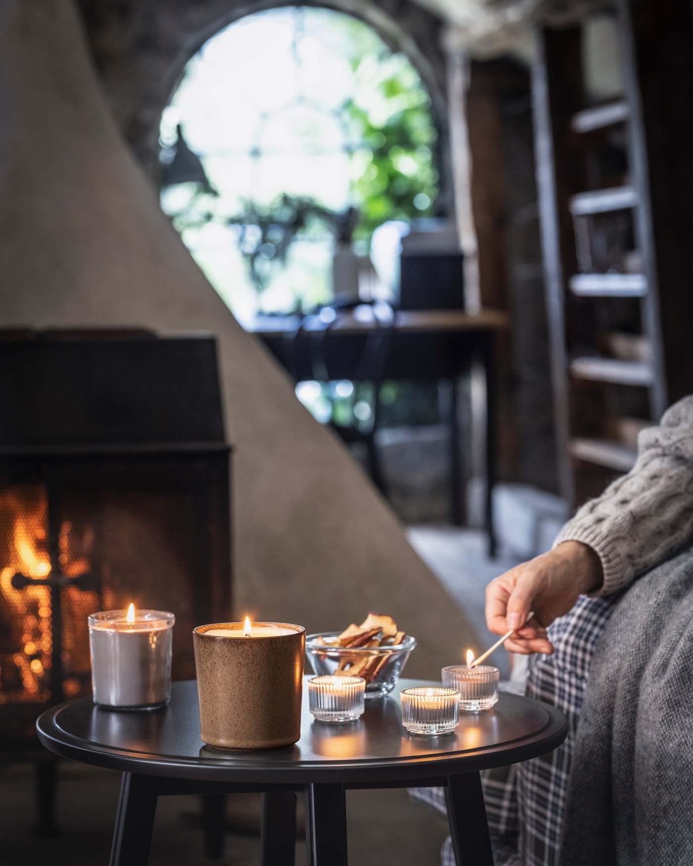A hand lights scented candles on the table. 
