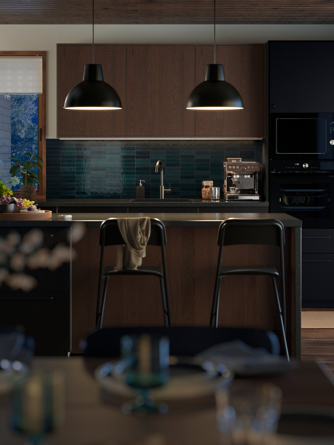 Two hanging pendant lamps are lighting up a kitchen island in a modern kitchen with fronts in brown and matt anthracite.