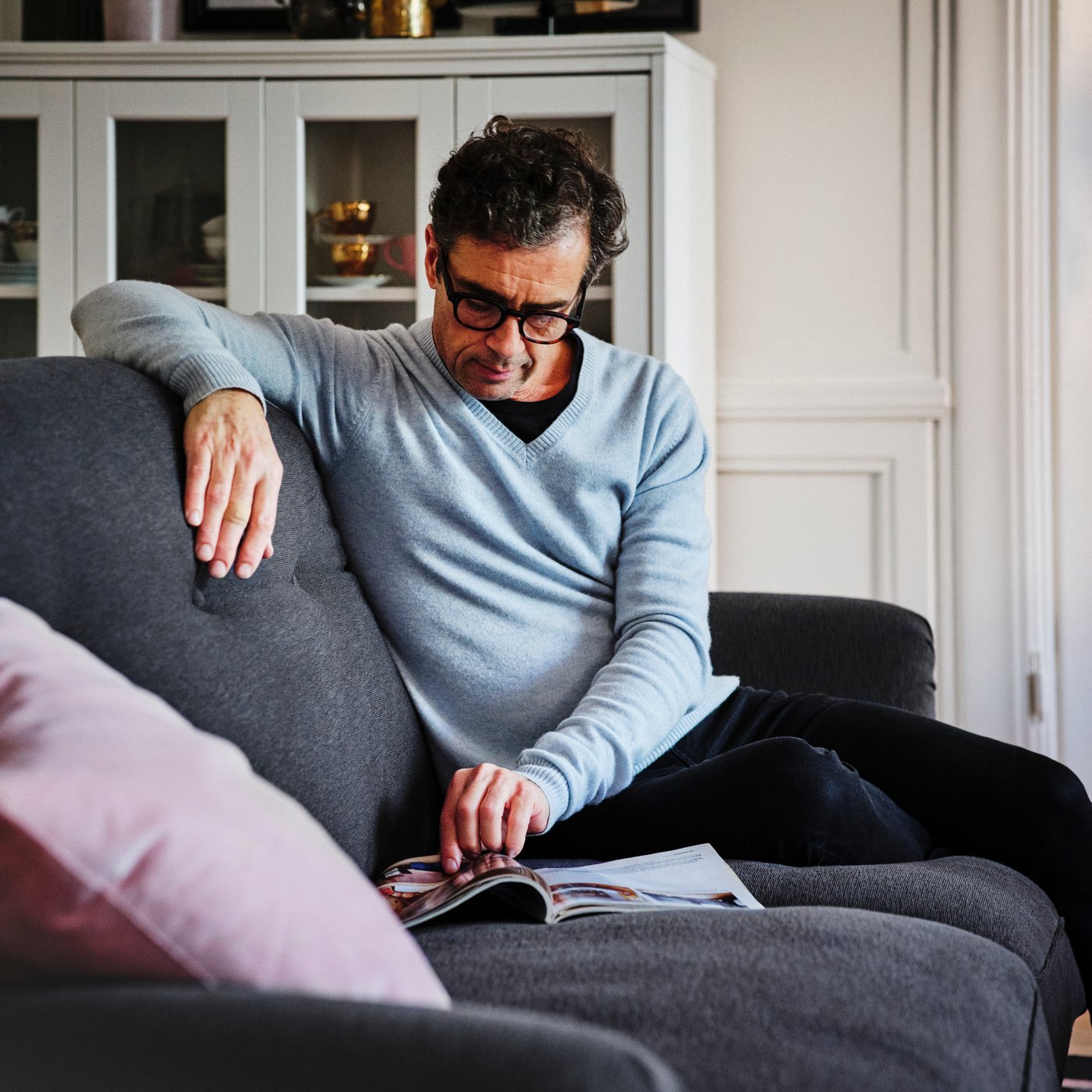 Eine Person sitzt auf einem weißen SÖDERHAMN Sofa und trinkt aus einer Tasse.