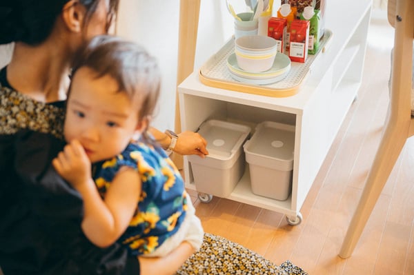 子どもを抱いて収納に手を伸ばす相談者