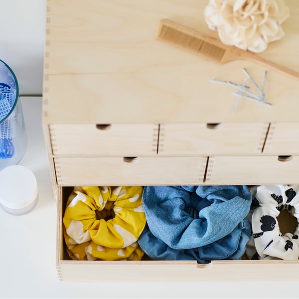 A birch plywood MOPPE mini chest with the bottom drawers open showing three rows of different colored hair scrunchies.