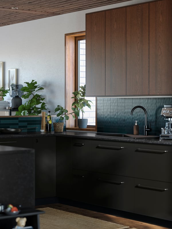 Une cuisine en U avec des planchers et un plafond en bois, des murs blancs, un carrelage vert et des façades de cuisine de tons brun et anthracite mat.
