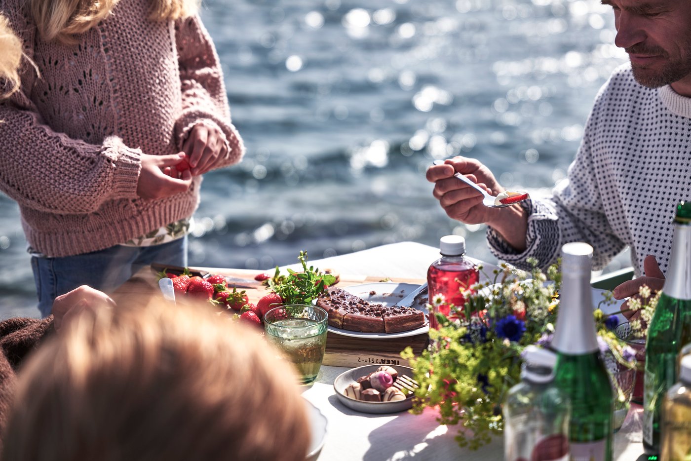 Kesäinen pöytä katettuna veden äärelle, tarjolla erilaisia makeita herkkuja.