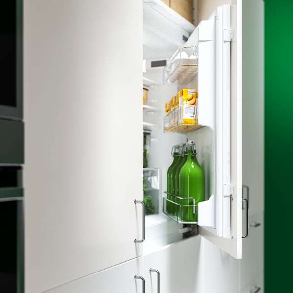 A fridge door of a built-in fridge/freezer is open and shows the bottles, juice boxes and food items that are stored inside.