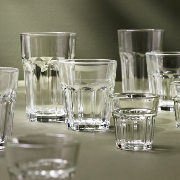 Several POKAL glasses of different sizes have been placed on a soft grey-green surface.