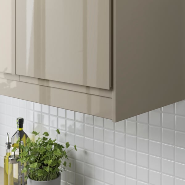 A VOXTORP wall cabinet with deco strip in high-gloss dark grey-brown.