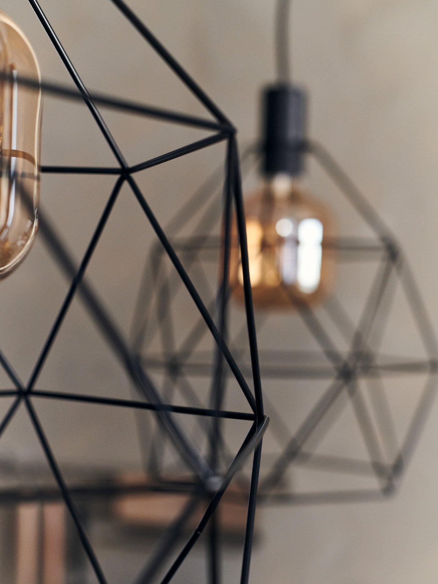 صورة مقربة لمصباح معلق BRUNSTA مع مصباح معلق BRUNSTA آخر في الخلفية.