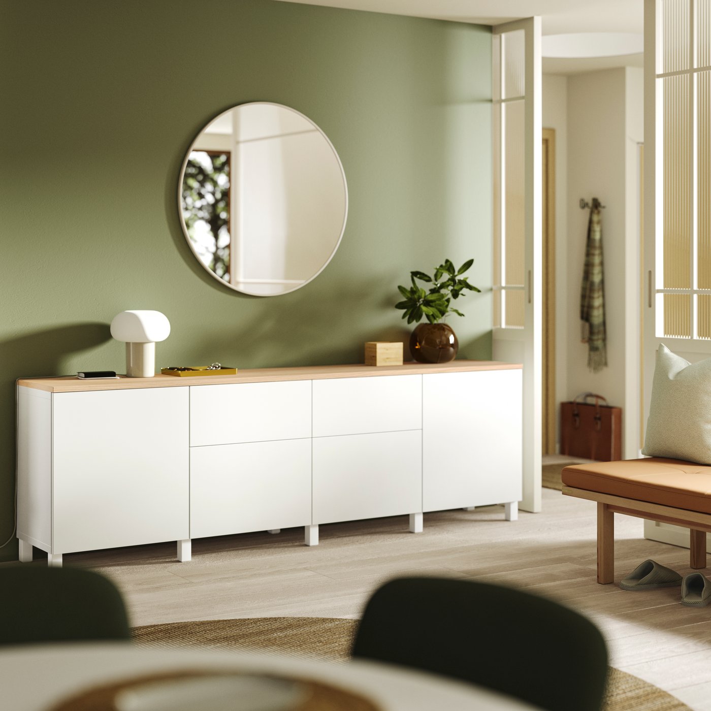 BESTÅ Sideboard mit rundem Spiegel und grüner Akzentwand im Flur.