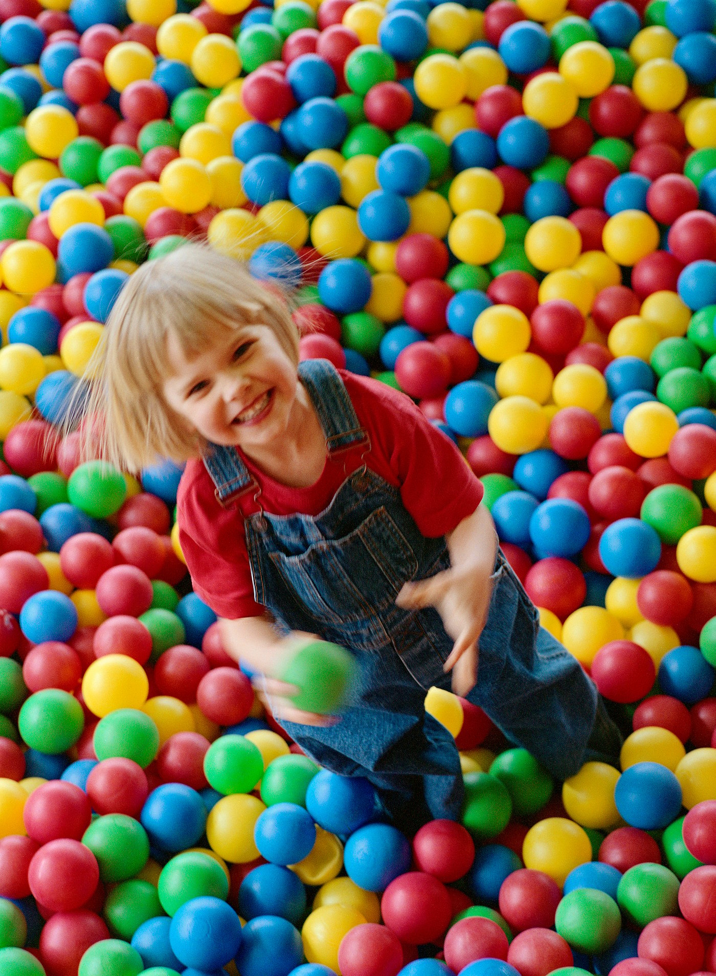 A little girl playing in a ball pit.