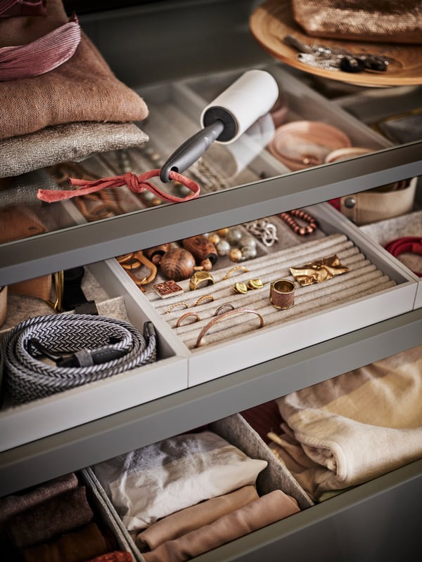 Two KOMPLEMENT pull-out trays with inserts holding accessories like jewellery and belts. A lint roller is on a shelf above.