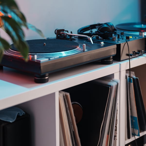 Un lettore di vinili su uno scaffale bianco con dischi in vinile.