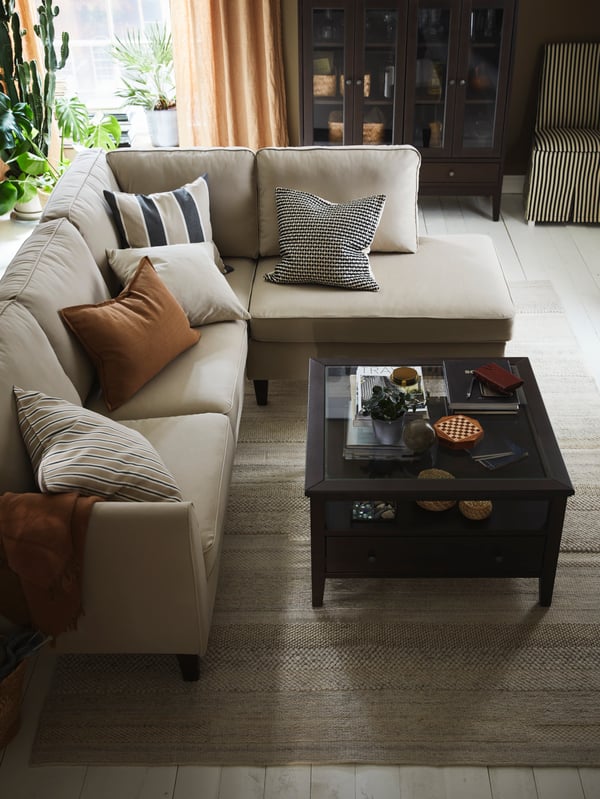 An L-shaped EKHOLMA corner sofa with five extra cushions and an IDANÄS coffee table stand in the centre of a living room.