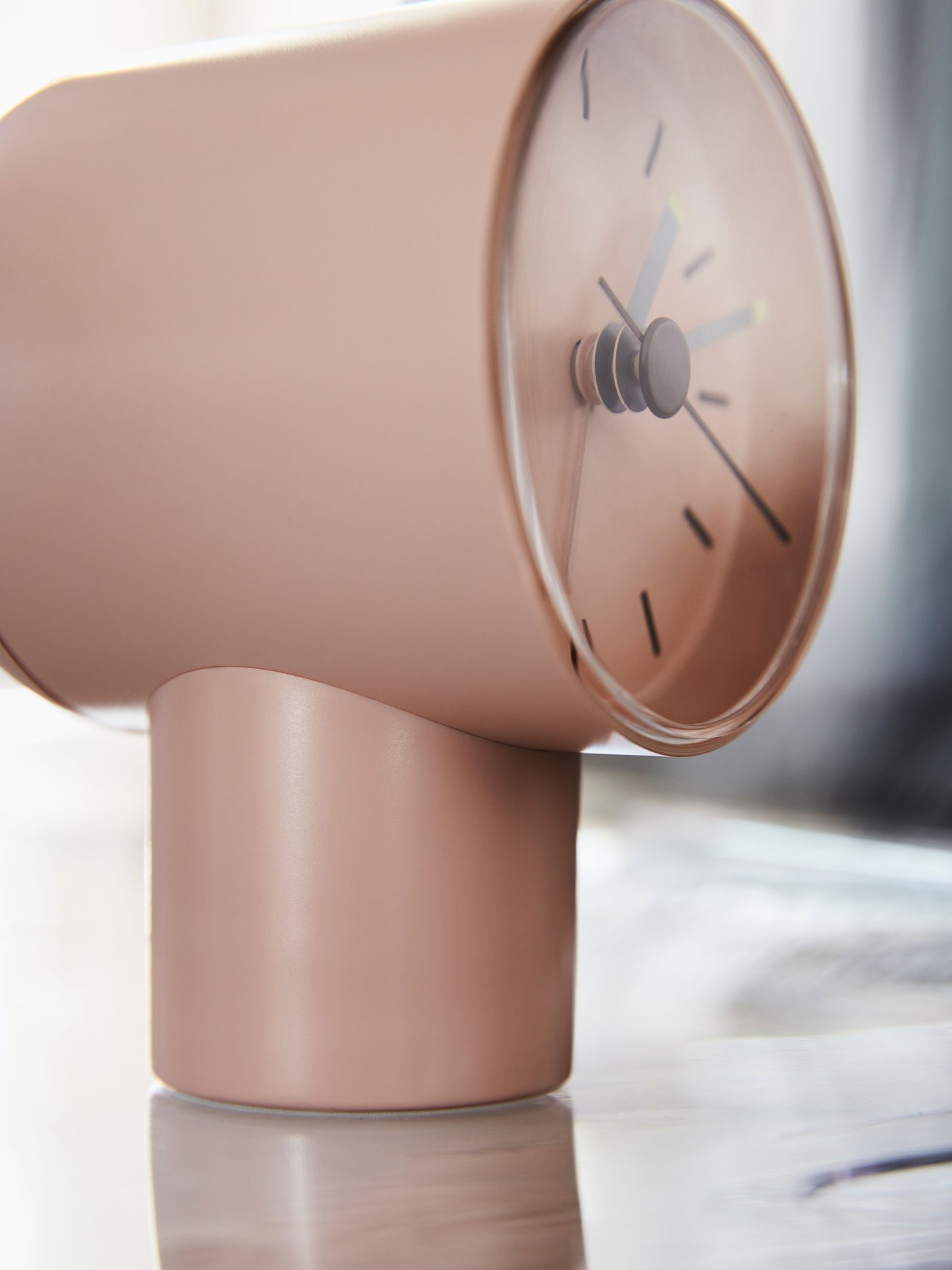 Une surface légèrement ensoleillée sur laquelle se trouve un réveil analogique BONDTOLVAN rose pâle.