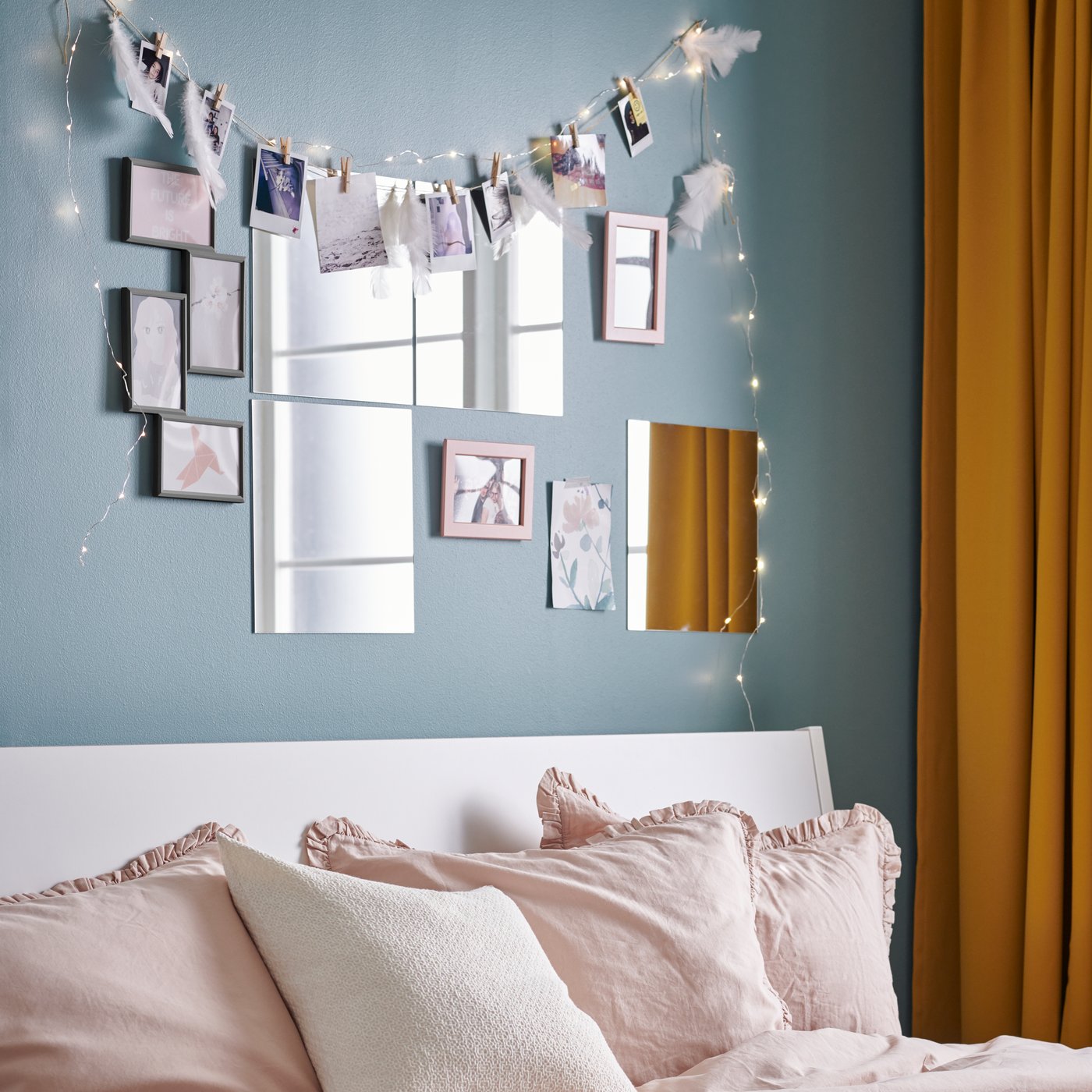 Decoración de habitación con espejos y fotos sobre pared azul