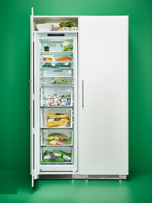Front shot of a white FORSNAS fridge with one door open, revealing multiple food items kept in food containers and bags.