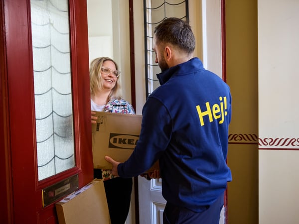 Un collaborateur IKEA apportant des colis IKEA à une cliente sur le pas de sa porte.