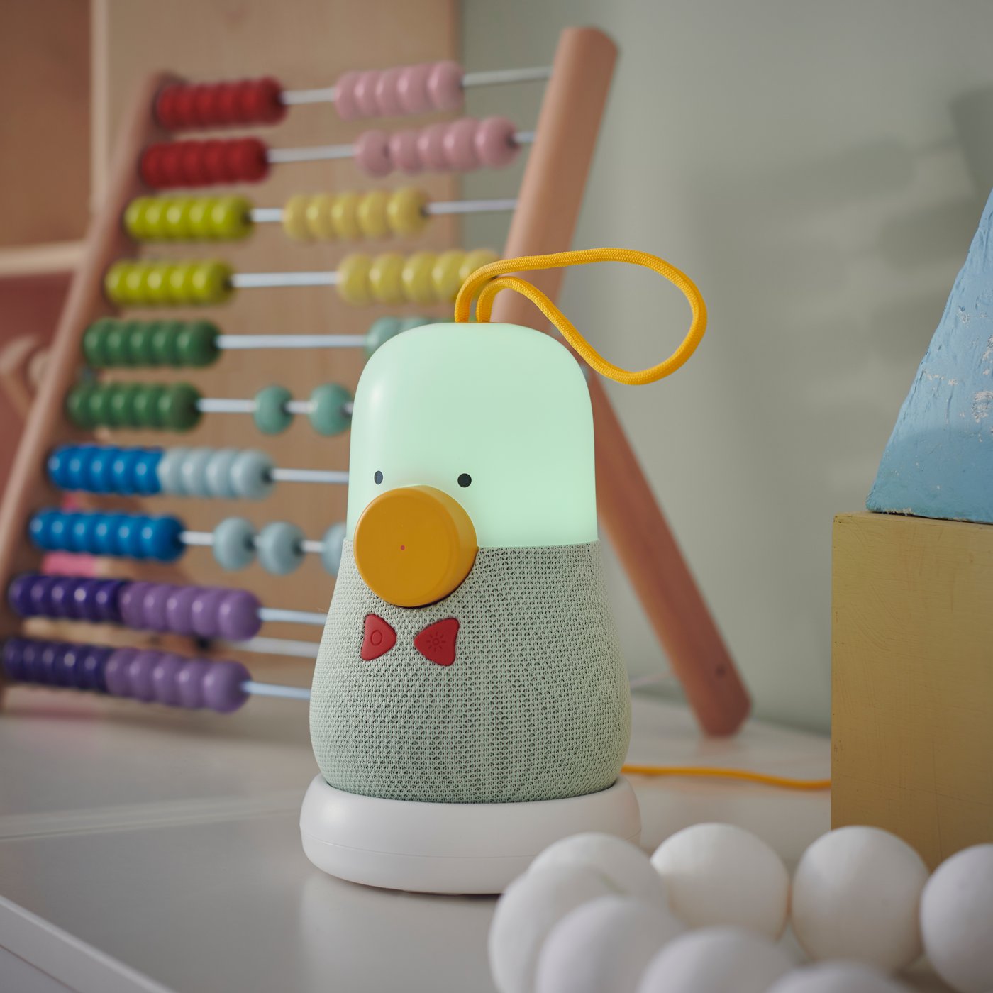 A VAPPEBY bluetooth speaker in a peanut shape is placed next to an UNDERHÅLLA abacus.