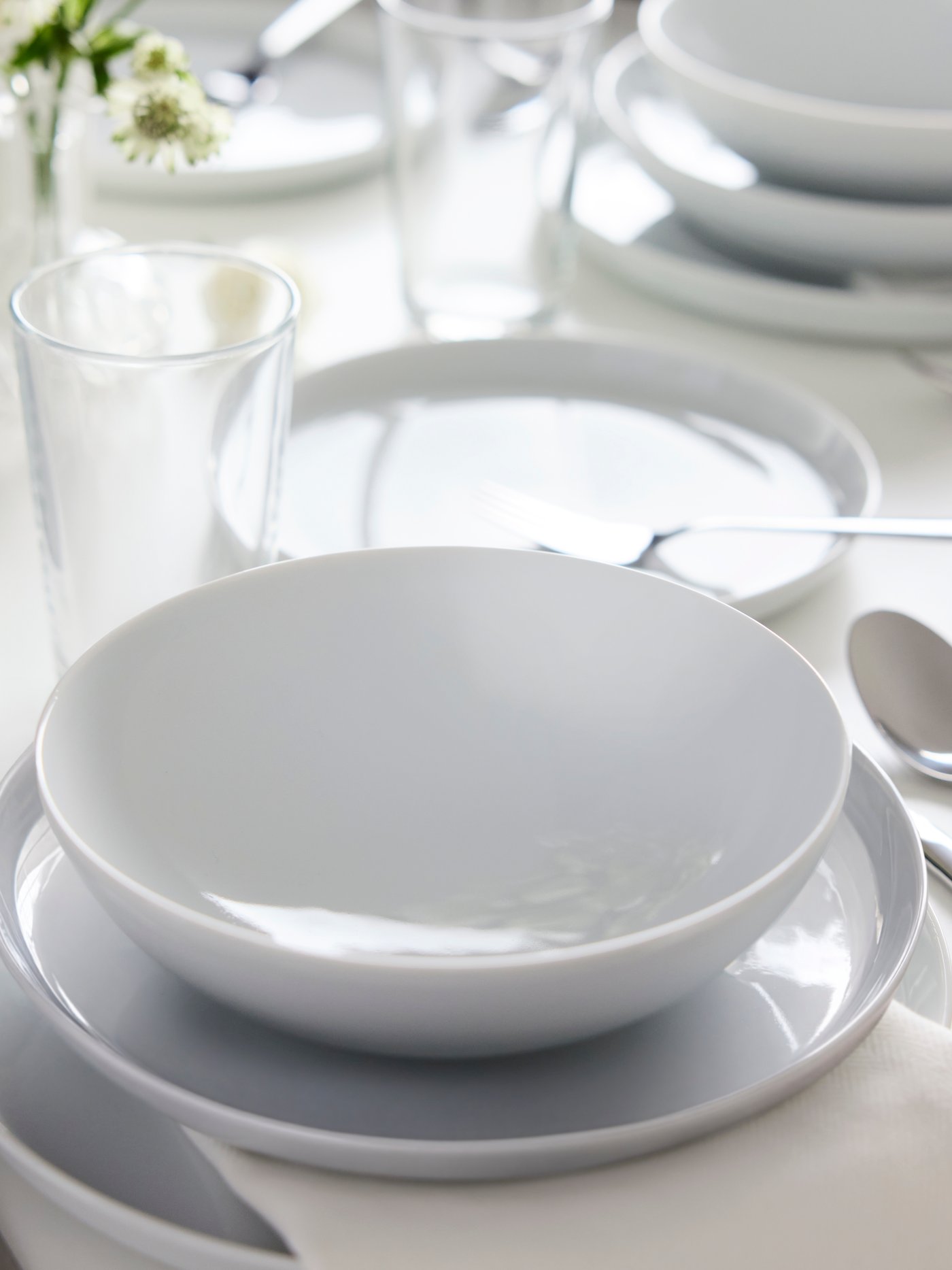 A place setting with a white IKEA 365+ bowl on top of a white IKEA 365+ side plate on top of a white IKEA 365+ plate.