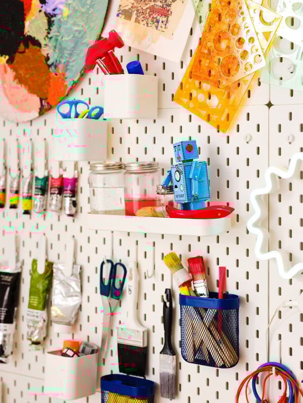 A SKÅDIS pegboard with hanging organizers, with art supplies in them.