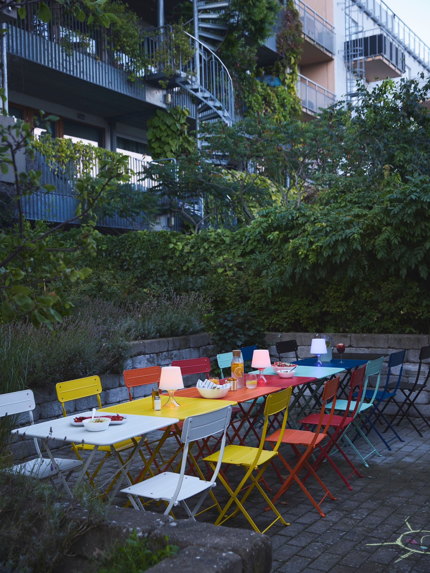 Verschiedene, bunte SUNDSÖ Klappstühl und Tische für draußen