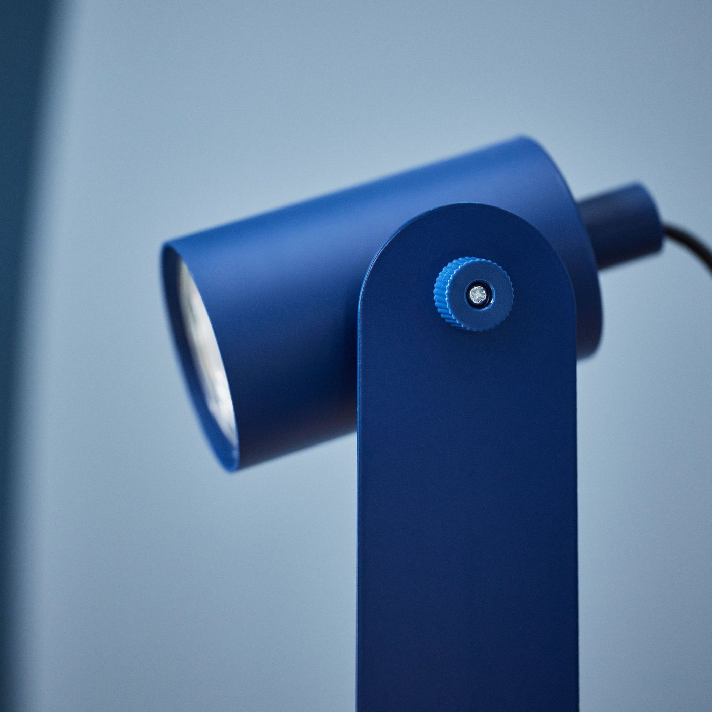 Vista laterale di una lampada IKEA blu con la testa orientata verso il basso.