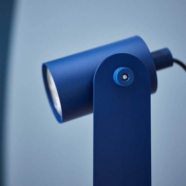 A blue Ikea lamp in profile that is directed diagonally downwards.