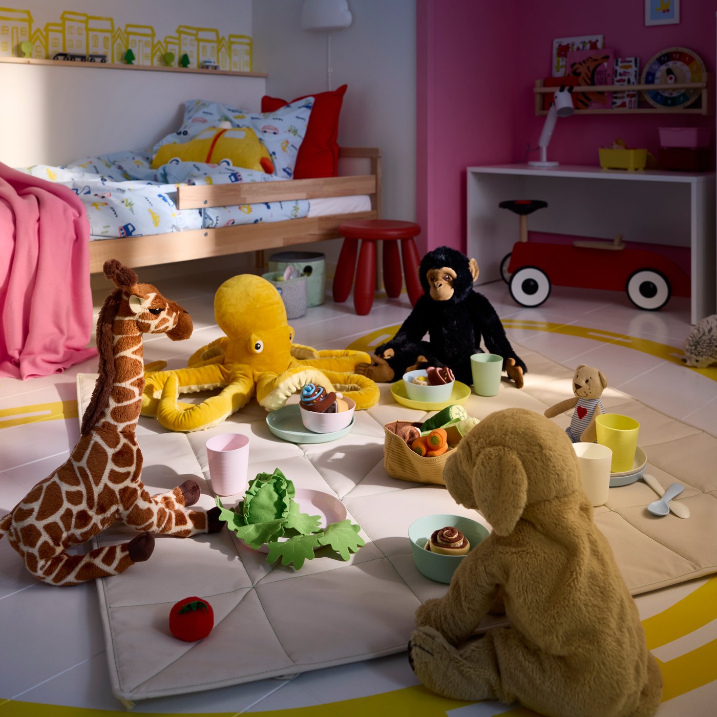 A play area with the BLÅVINGAD soft toy placed among other plush animals having a picnic in a children’s room.