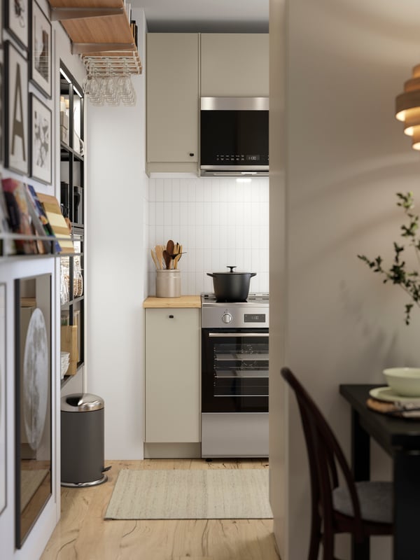 A kitchen with beige HAVSTORP fronts is seen from the dining area and there’s a black drop-leaf table in the foreground.