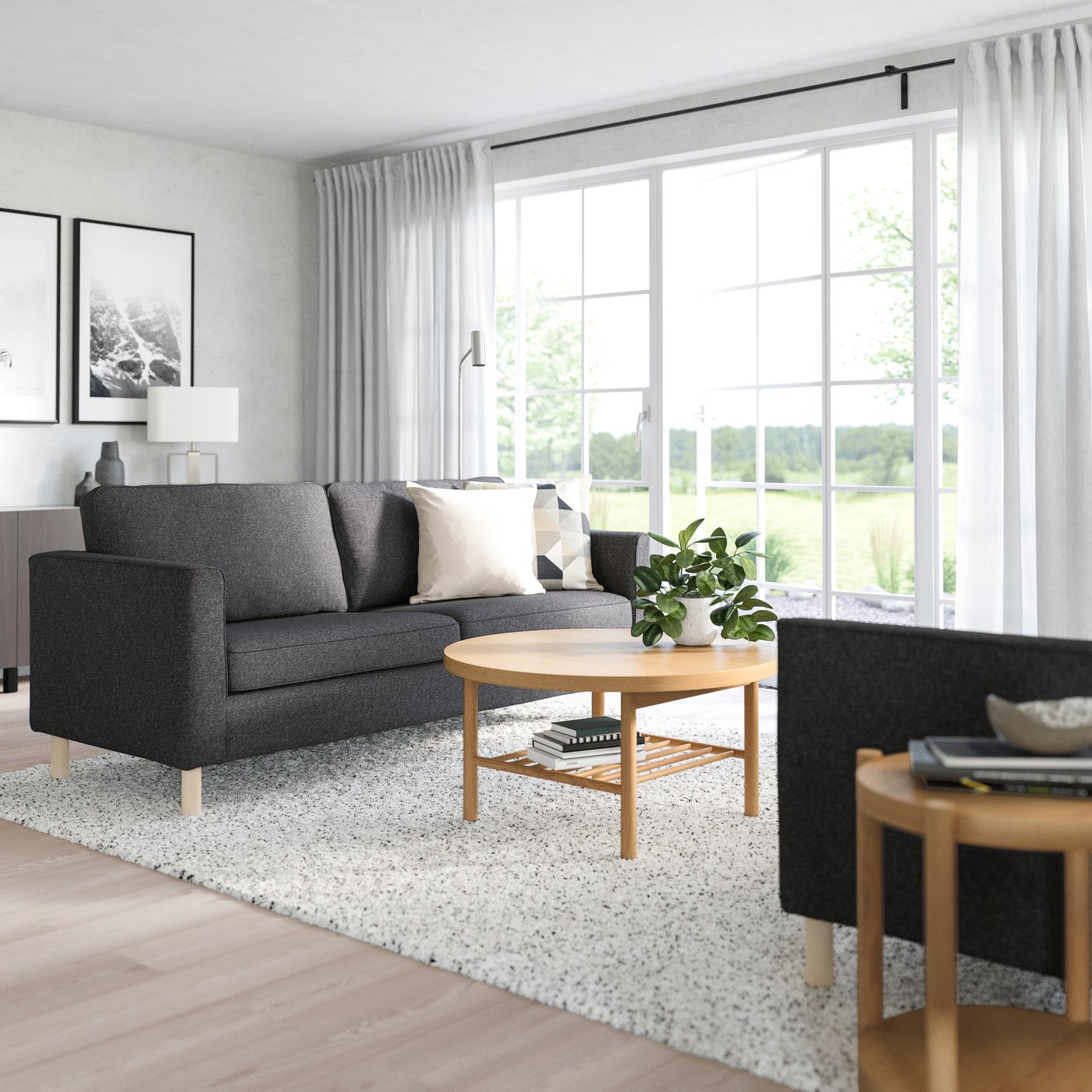 Living room with a dark gray sofa, round wood coffee table, and large windows filling the space with natural light.