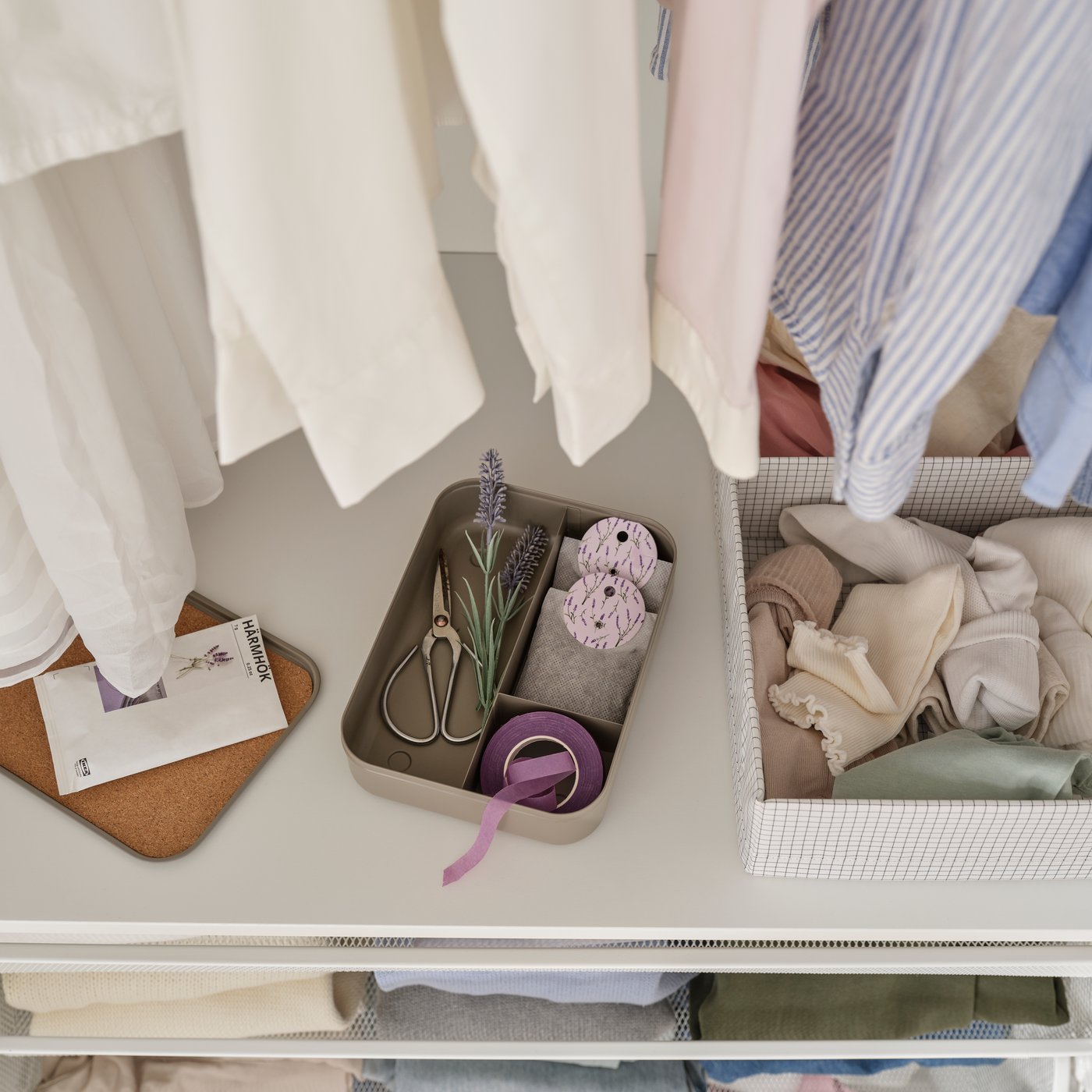 A close-up of a HARVMATTA box with compartments holding sewing supplies and lavender sachets on a shelf in a wardrobe.