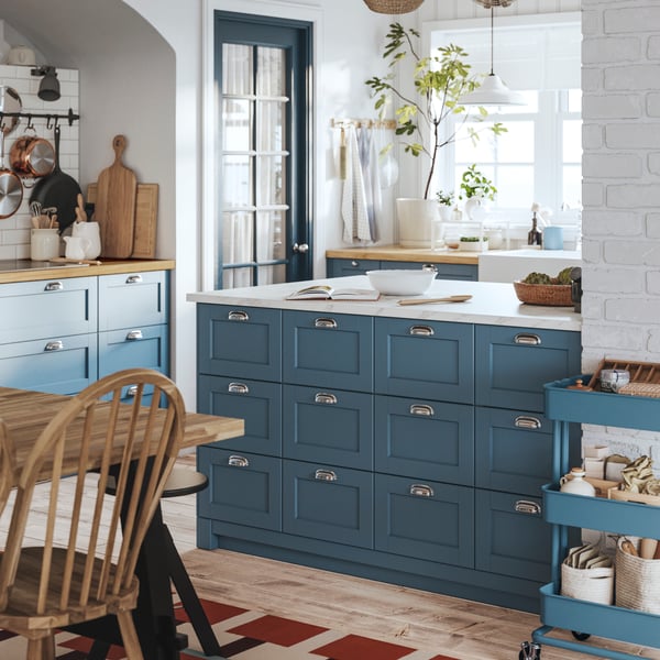 A kitchen island made of SEKTION cabinets has several drawers with LERHYTTAN blue fronts and chrome-plated ENERYDA handles.