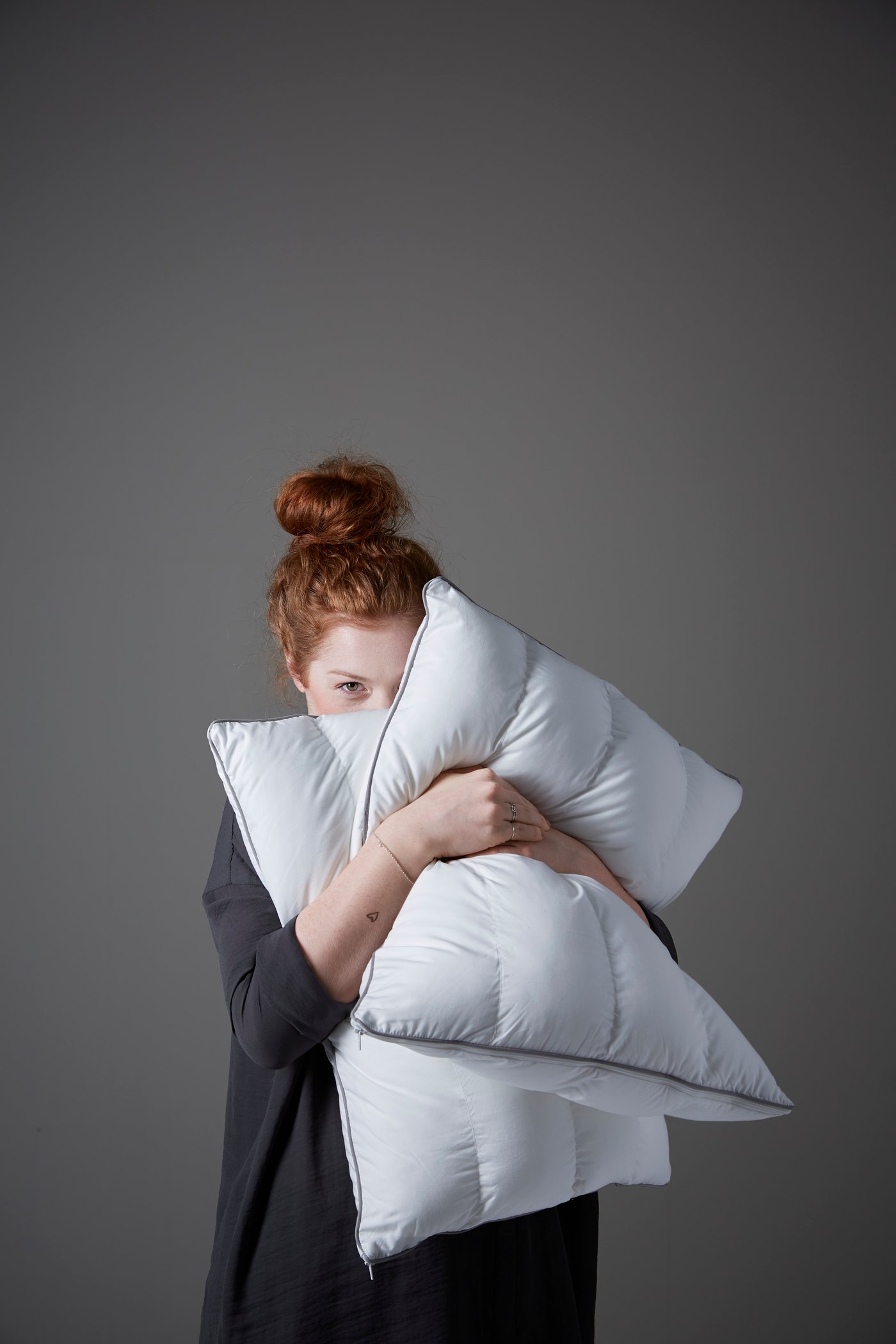 une femme tenant deux oreillers dans ses bras