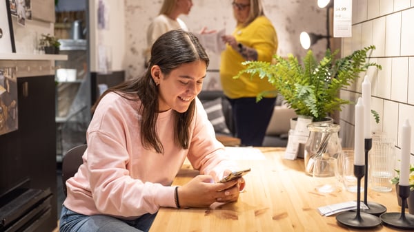 Une femme utilise un téléphone intelligent dans un magasin IKEA.