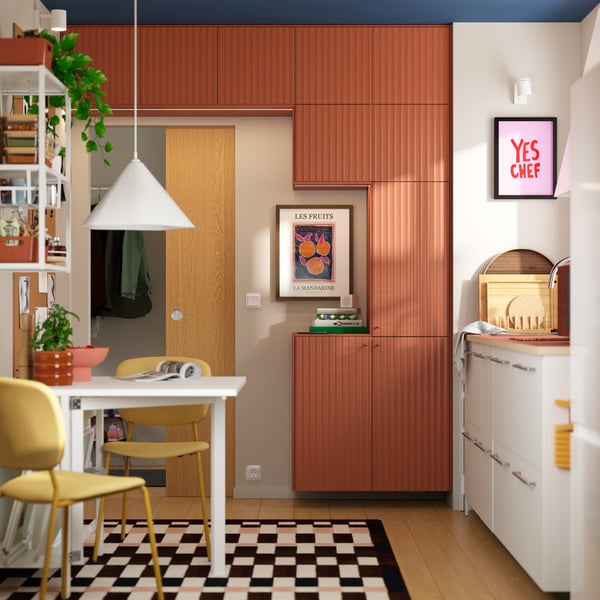 Une petite cuisine qui possède des placards avec un mélange de portes décoratives TERRSJÖ à motif ondulé rouge-brun et de façades blanches VALLSTENA.