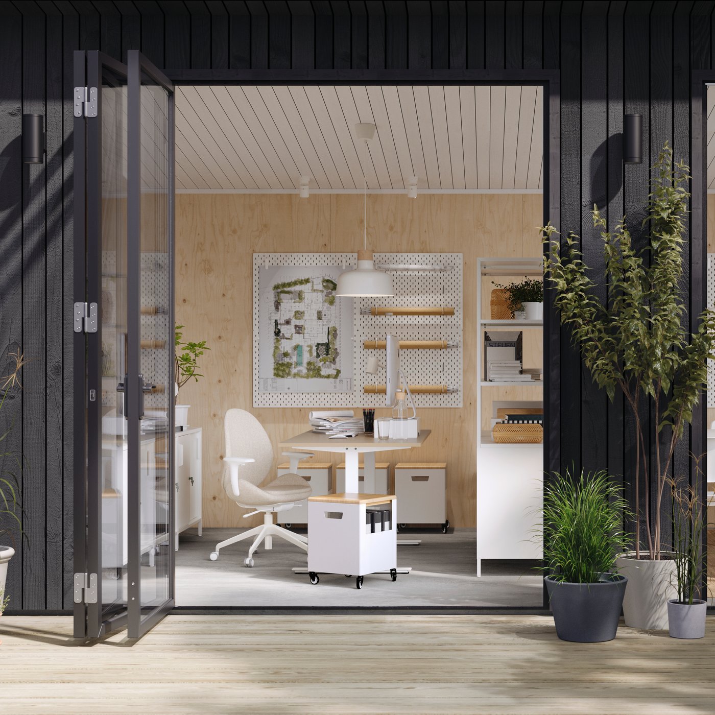 A garden studio with open doors showing a desk and chair work area, open shelving divider and a communal kitchen area.