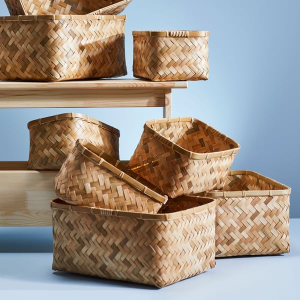 A variety of woven baskets in different shapes and sizes displayed on wooden shelves against a blue background.