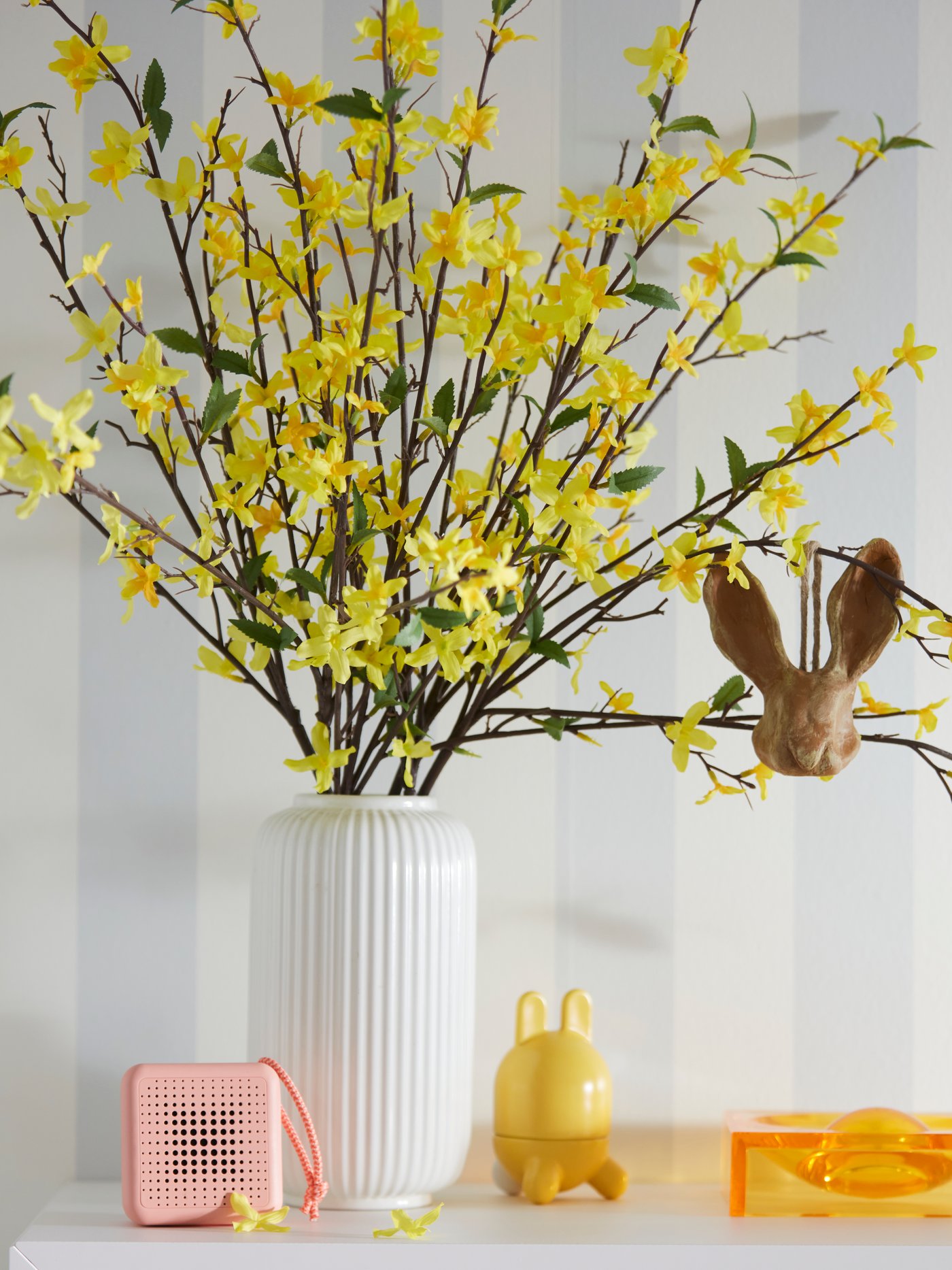 Yellow artificial flowers in a white vase