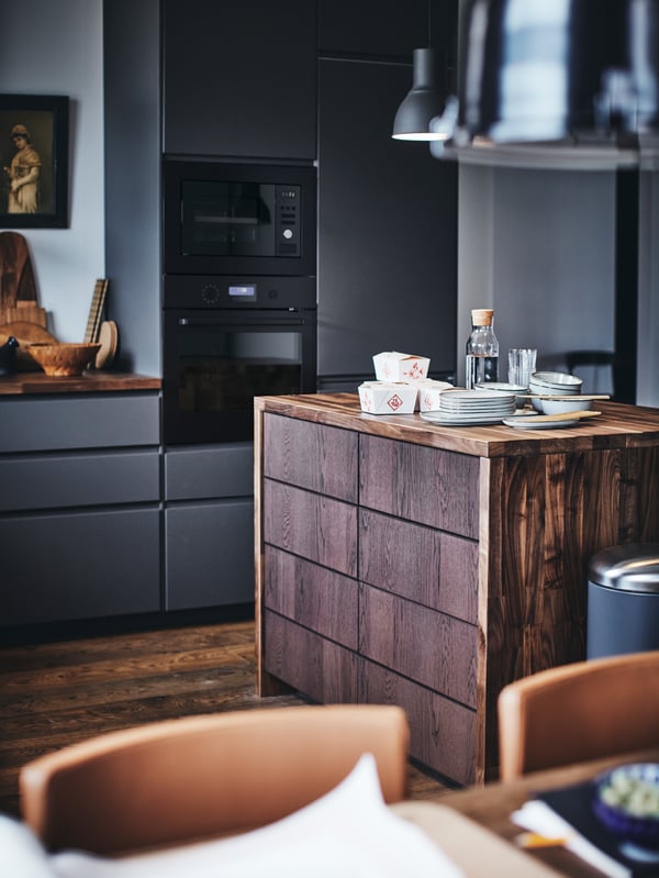 A METOD kitchen with a wooden kitchen island with plates and takeaway food containers on top.