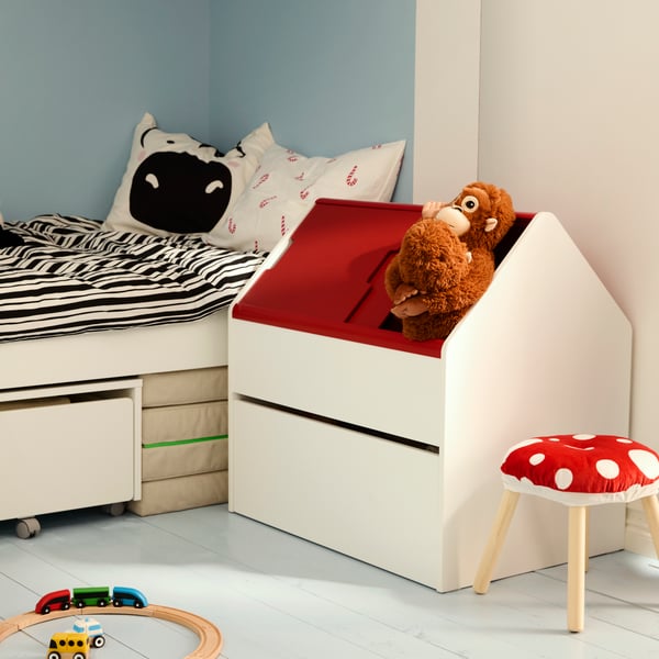 L’angle d’une chambre d’enfant avec un lit et un rangement VITBJÖRN. Peluches sortant du toit d’un rangement VITBJÖRN.