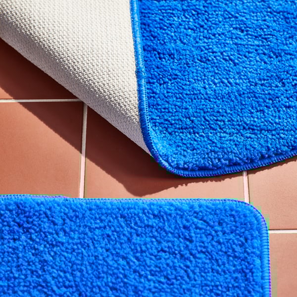 Un tappetino da bagno blu BERGVATTNET nel bagno.