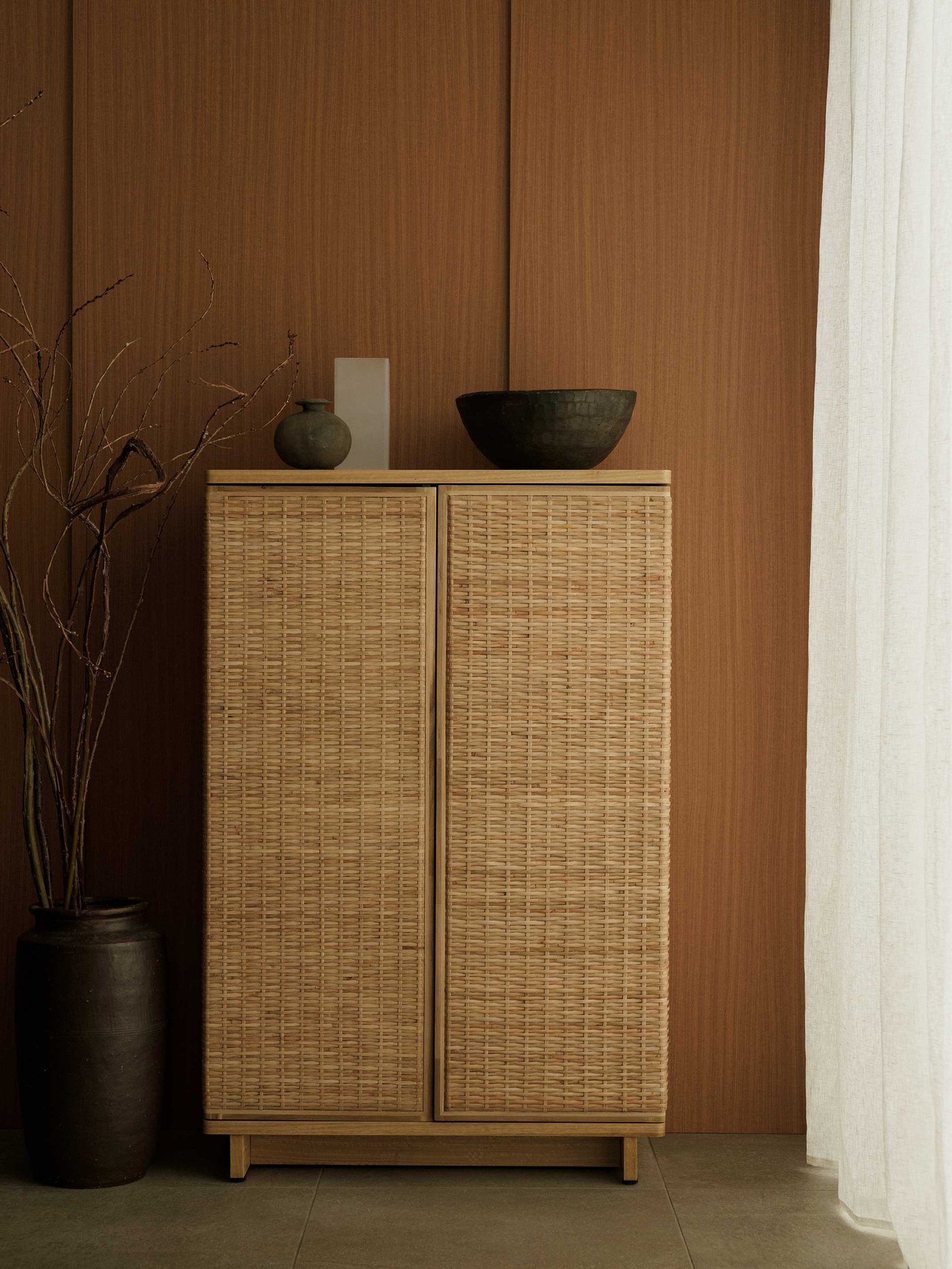 Rottinkinen FRYKSÅS-kaappi poltetun oranssia seinää vasten.